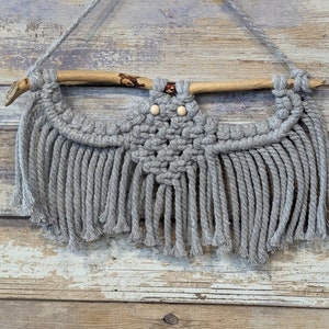 May include: Gray macrame owl wall hanging with wooden branch and wooden beads for eyes.
