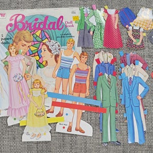 K&ouml;nnte beinhalten: Ein Vintage "Bridal Doll Book" mit Papierpuppen und Outfits. Das Cover zeigt Illustrationen eines Brautpaares. Das Set enth&auml;lt Papierpuppen einer Braut, Brautjungfern und Br&auml;utigame sowie verschiedene Outfits f&uuml;r ein Hochzeitsthema.