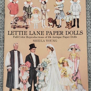 K&ouml;nnte beinhalten: Ein Vintage-Buchcover mit dem Titel "LETTIE LANE PAPER DOLLS" und dem Untertitel "Full-Color Reproductions of 24 Antique Paper Dolls" von Sheila Young. Das Cover zeigt Illustrationen von Papierpuppen in verschiedenen Outfits, darunter Kinder und Erwachsene.