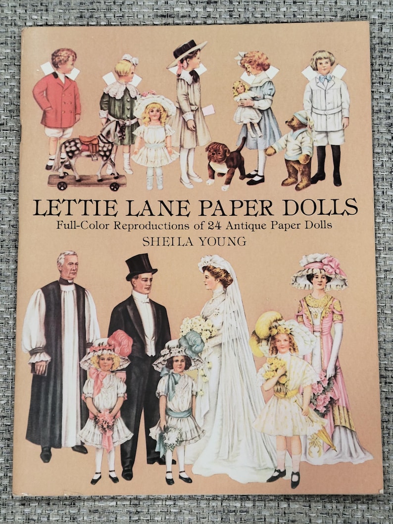 K&ouml;nnte beinhalten: Ein Vintage-Buchcover mit dem Titel "LETTIE LANE PAPER DOLLS" und dem Untertitel "Full-Color Reproductions of 24 Antique Paper Dolls" von Sheila Young. Das Cover zeigt Illustrationen von Papierpuppen in verschiedenen Outfits, darunter Kinder und Erwachsene.