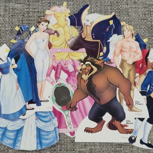 K&ouml;nnte beinhalten: Papierpuppen mit Charakteren aus Disneys Die Sch&ouml;ne und das Biest. Enth&auml;lt Belle, das Biest, Gaston und andere Charaktere. Die Puppen haben Outfits und Accessoires in verschiedenen Farben, darunter Blau, Gelb und Rosa.