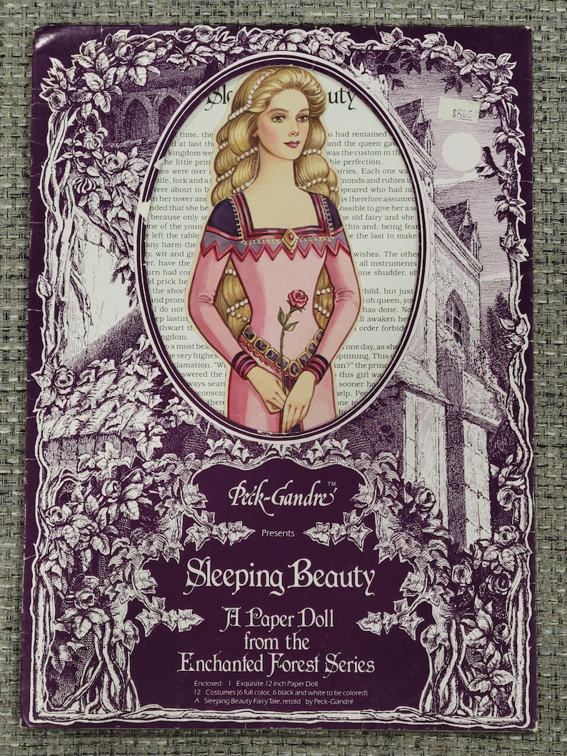 K&ouml;nnte beinhalten: Ein Vintage-Papierpuppen-Set "Sleeping Beauty" aus der "Enchanted Forest Series" von Peck-Gandre. Das Cover zeigt eine Illustration einer Prinzessin in einem rosa Kleid, umgeben von einem floralen Rand. Das Set enth&auml;lt eine 30,48 cm gro&szlig;e Papierpuppe und Kost&uuml;me.