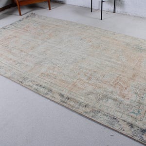 May include: A rectangular area rug featuring a faded, distressed pattern in muted shades of beige, cream, and soft blue-gray. The design includes a central medallion motif surrounded by an intricate border, all with a worn, weathered appearance.