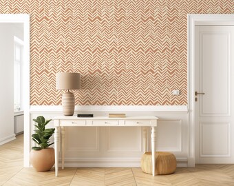 May include: A white console table with four drawers and a brown lamp on top. The table is in a room with beige walls and a brown and white chevron patterned wallpaper. There is a potted plant and a small stool in the room.