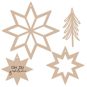 Può includere: Set di cinque decorazioni natalizie in legno beige. Le decorazioni sono a forma di stelle e di un albero di Natale. Una stella ha il testo "OH DU fröhliche" scritto su di essa.