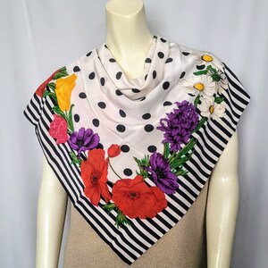 May include: A square silk scarf with a white background and black polka dots. The scarf features a floral design with red poppies, purple anemones, yellow tulips, and white daisies. The border has black and white stripes.