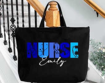 May include: Black tote bag with the word "NURSE" in blue and white letters with medical symbols incorporated into the letters. The name "Emily" is written in white cursive below the word "NURSE".