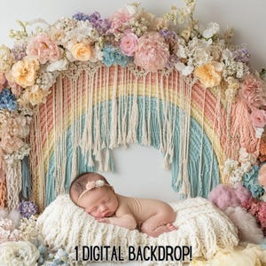 Puede incluir: Un telón de fondo digital con un arco de macramé arcoíris decorado con flores pastel. Un bebé recién nacido está durmiendo en una manta blanca y esponjosa frente al arco.