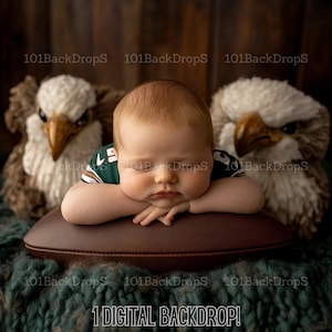 Könnte beinhalten: Ein neugeborenes Baby, das ein grün-weißes Fussballtrikot trägt, schläft auf einem braunen, fußballförmigen Kissen. Zwei weiße, flauschige Adlerfiguren befinden sich auf beiden Seiten des Babys.