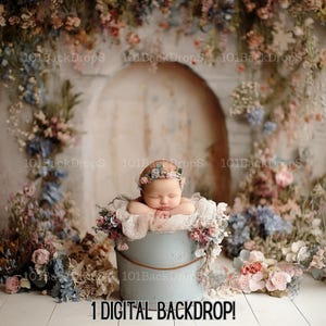 Peut inclure: Un nouveau-né, une petite fille portant une couronne de fleurs, dort paisiblement dans un seau bleu entouré d'un fond floral. La toile de fond présente une arche en pierre avec une porte patinée et une végétation luxuriante.