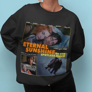 May include: Black sweatshirt with a graphic print of the movie "Eternal Sunshine of the Spotless Mind". The print features a collage of scenes from the film, including the main characters, Jim Carrey and Kate Winslet, and the film's title in yellow.