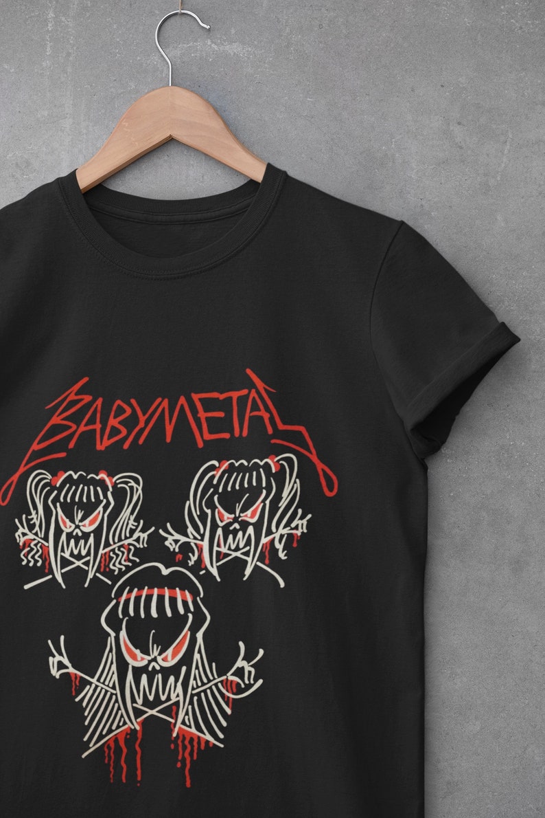 Pode incluir: Camiseta preta com um logotipo "BABYMETAL" vermelho e uma imagem de desenho animado branca de tr&ecirc;s meninas com presas e rabos de cavalo.
