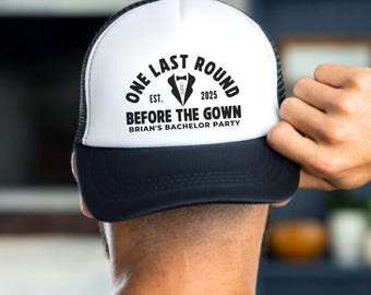 May include: A black and white trucker hat with the text "One Last Round Est. 2025 Before The Gown Brian's Bachelor Party" on the front.