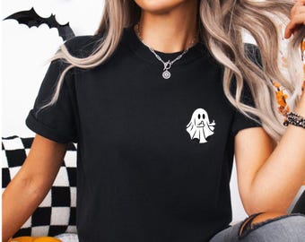 May include: Black t-shirt with a white ghost graphic giving the middle finger. The ghost is on the left side of the shirt.