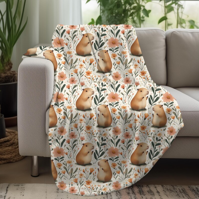 May include: A white throw blanket with a repeating pattern of brown guinea pigs and orange flowers. The guinea pigs are sitting upright with their paws in the air.