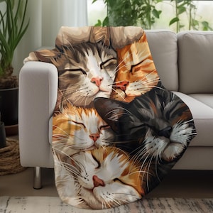 May include: A soft, cozy fleece blanket featuring a colorful illustration of four cats sleeping together. The cats are a tabby, a calico, a black and white cat, and a ginger cat. The blanket is perfect for cuddling up on the couch or in bed.