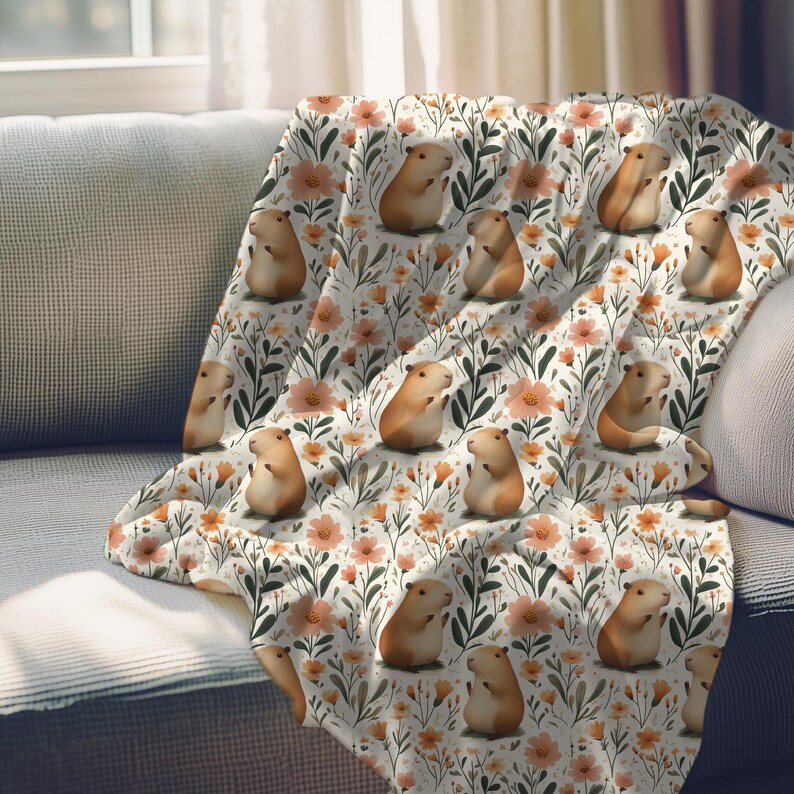 May include: A white throw blanket with a repeating pattern of brown guinea pigs and orange flowers. The guinea pigs are sitting up and have their paws in the air.