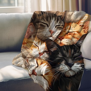 May include: A soft, cozy blanket featuring a close-up image of four cats sleeping together. The cats are a mix of brown, black, and white fur. The blanket is perfect for cuddling up on the couch or in bed.