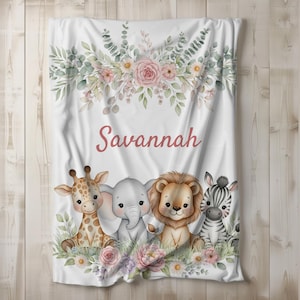 May include: White baby blanket featuring a floral design with pink roses and greenery. The blanket has the name "Savannah" in pink script, and illustrations of a giraffe, elephant, lion, and zebra.