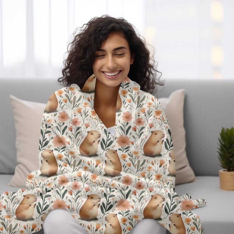 May include: A white throw blanket with a floral pattern featuring small brown and white guinea pigs. The blanket is made of soft, cosy fabric and is perfect for snuggling up on the sofa.