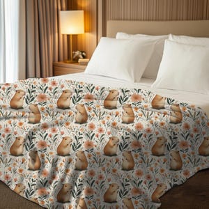 May include: A white duvet cover with a repeating pattern of brown guinea pigs and orange flowers. The guinea pigs are sitting up and looking to the right. The flowers are small and scattered throughout the pattern.