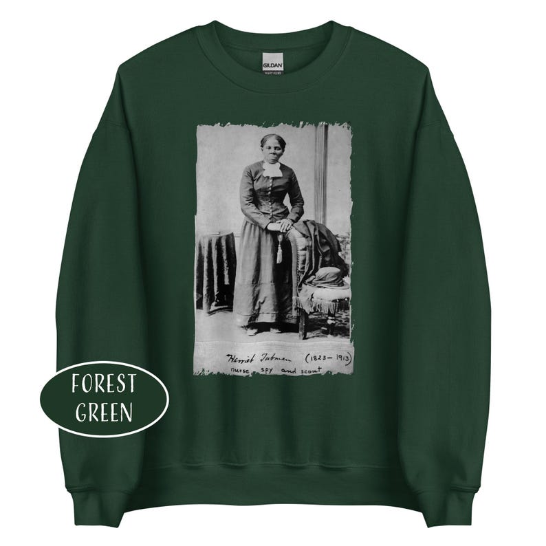 May include: Forest green sweatshirt featuring a black and white image of Harriet Tubman. The image is framed with a white border and includes the text "Harriet Tubman (1822-1913) nurse, spy and scout."
