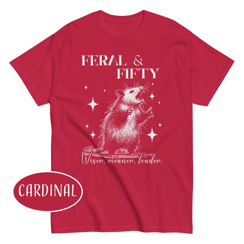 May include: Cardinal red t-shirt with a white graphic of an opossum and the text "FERAL & FIFTY". Below the graphic is the text "Wiser, meaner, louder."