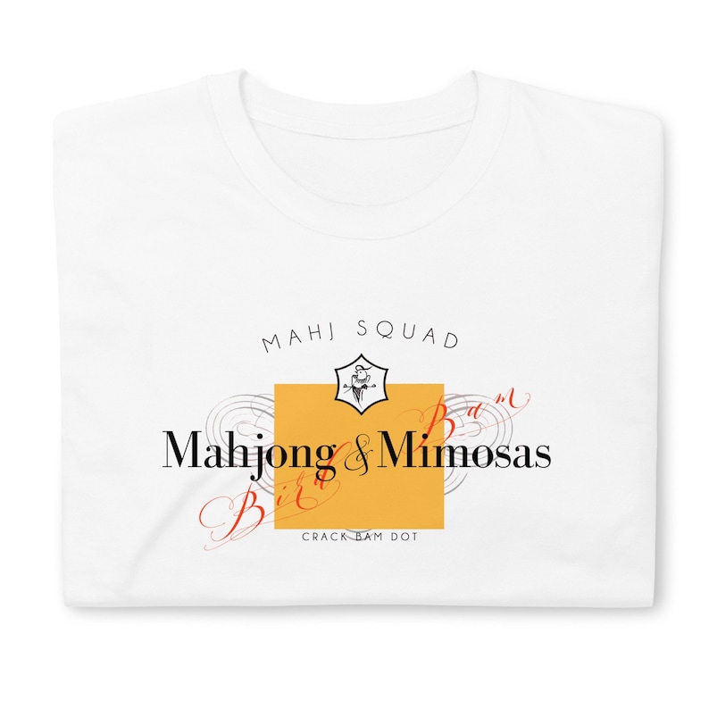 May include: White t-shirt with a yellow square and black text that reads "Mahj Squad" and "Mahjong & Mimosas Bit*" with a small bird graphic above the text. The text "Crack-Bam Dot" is below the square.