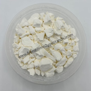 May include: A clear plastic bowl filled with irregular, solid white chunks of starch. The text www.fromhome2youstarch..com is printed across the center of the bowl, overlaying the white pieces of starch contained within the transparent vessel.
