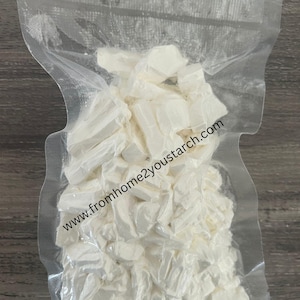 May include: A clear vacuum-sealed plastic bag filled with irregular, solid white chunks of starch. The text www.fromhome2youstarch.com is printed diagonally across the front of the transparent packaging, which contains numerous small, opaque white pieces.