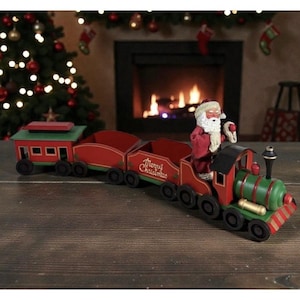 May include: A decorative Christmas train with Santa Claus riding in the engine. The train is red and green with the words "Merry Christmas" on the side. The train is on a wooden surface.