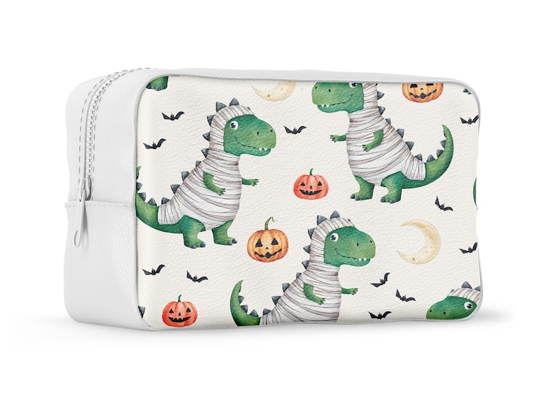 May include: White zippered pouch with a Halloween-themed print featuring green mummies dressed as dinosaurs, orange pumpkins, and black bats.