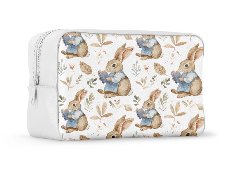 May include: White zippered makeup bag with a repeating pattern of brown rabbits holding blue books and brown leaves on a white background.