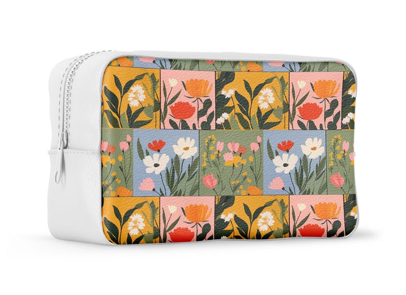 May include: White zippered pouch with a floral pattern. The pattern features a variety of flowers in shades of pink, orange, yellow, blue, and green. The flowers are arranged in a patchwork design.