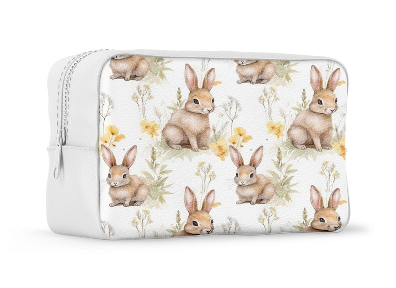 May include: White zippered pouch with a repeating pattern of brown bunnies and yellow flowers on a white background.