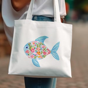 White tote bag with a colorful floral fish illustration.