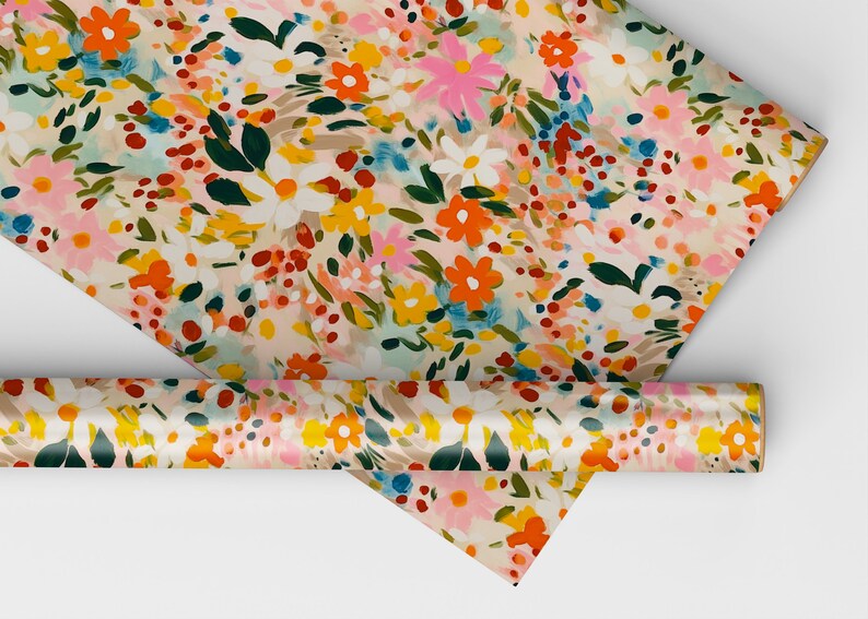 Pu&ograve; includere: Un rotolo di carta da regalo con motivo floreale su sfondo bianco e fiori colorati in tonalit&agrave; di rosa, arancio, giallo, blu e verde.