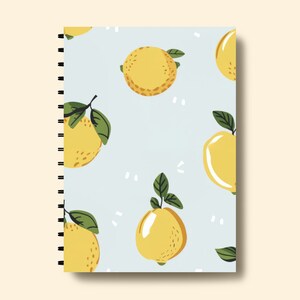 Puede incluir: Una libreta azul con encuadernaci&oacute;n en espiral presenta un patr&oacute;n repetitivo de limones amarillos con hojas verdes sobre un fondo azul claro.