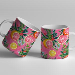May include: Two white ceramic mugs with a pink background and a pattern of lemons, grapefruits, and green leaves.