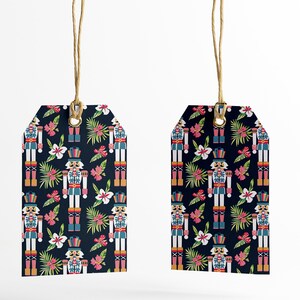 Pu&ograve; includere: Due etichette regalo blu con un motivo ripetitivo di schiaccianoci e fiori tropicali. Le etichette sono appese a uno spago.