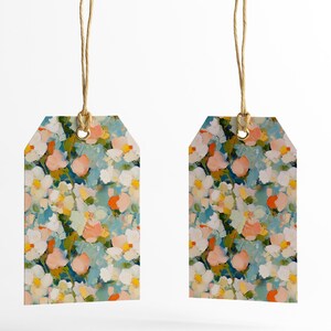 May include: Two gift tags with a floral pattern. The tags are white with blue, pink, yellow, and orange flowers. The tags are tied with twine.
