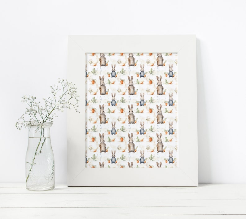 May include: A white framed print with a repeating pattern of brown rabbits holding carrots on a white background with green leaves and orange flowers.