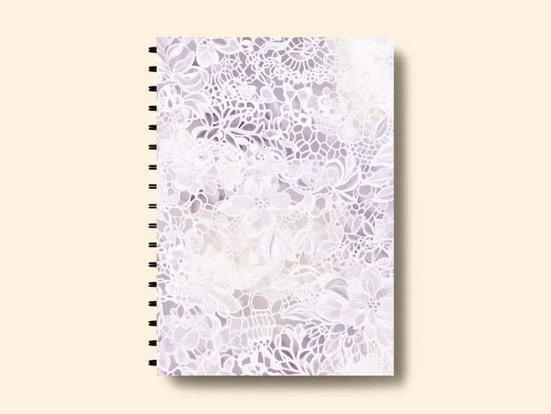 May include: A spiral bound notebook with a white lace pattern on a purple background.