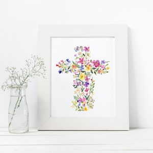 May include: A white framed print with a watercolor painting of a cross made of colorful flowers. The flowers are in shades of pink, purple, yellow, and blue.