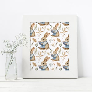 May include: A white framed print with a repeating pattern of brown rabbits wearing blue shirts and holding books. The rabbits are surrounded by brown leaves and green foliage.