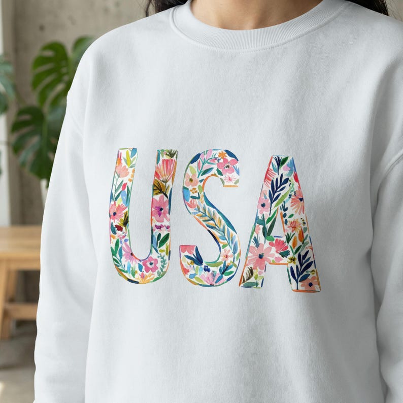 White sweatshirt with "USA" in colorful floral letters.