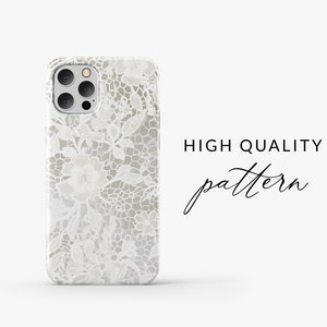 May include: A white phone case featuring a delicate lace pattern. The case has a cut-out for the camera lens.