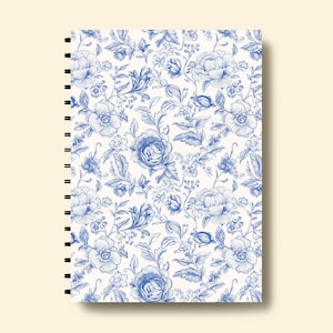 May include: A white spiral bound notebook with a blue floral pattern. The pattern features blue flowers and leaves on a white background.