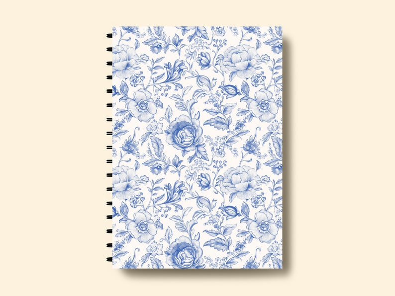 May include: A white spiral bound notebook with a blue floral pattern. The pattern features blue flowers and leaves on a white background.