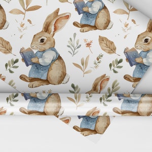 May include: A white wrapping paper with a repeating pattern of brown rabbits holding blue books, surrounded by green and brown leaves.